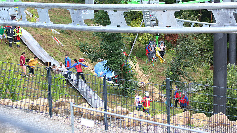 Bergwacht und Feuerwehr seilen Besucher aus der stehenden Gondelbahn der neuen Sommerrodelbahn "Hexenbesen" ab.