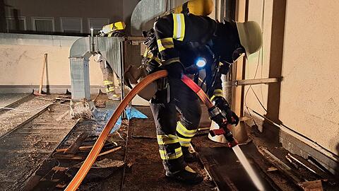 Ein Feuerwehrmann bekämpft vom Flachdach aus den Brand. Foto: Feuerwehr