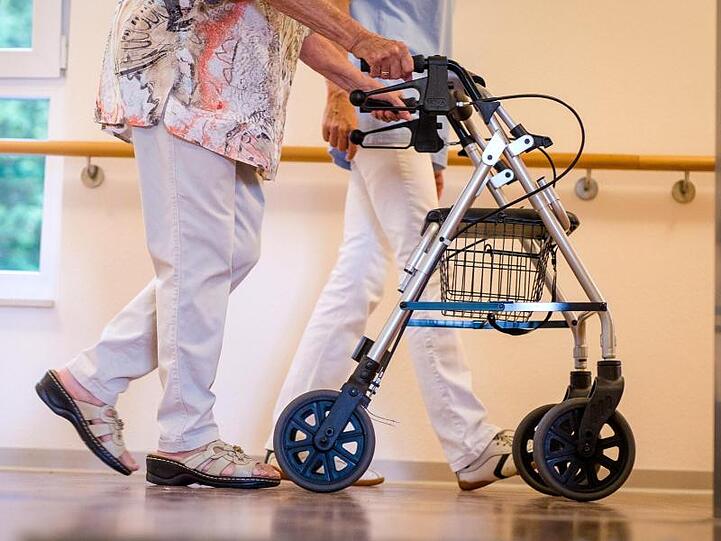 Eine Pflegekraft geht in einem Pflegeheim mit einer älteren Dame über einen Korridor. Künftig sollen Beschäftige in der Alten- und Krankenpflege besser bezahlt werden.