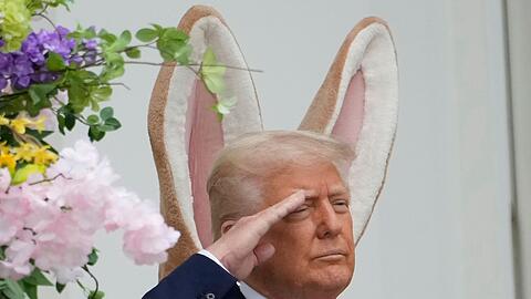 Donald Trump steht vor einem großen Osterhasen - und es sieht so aus, als hätte er sich die Ohren geliehen.