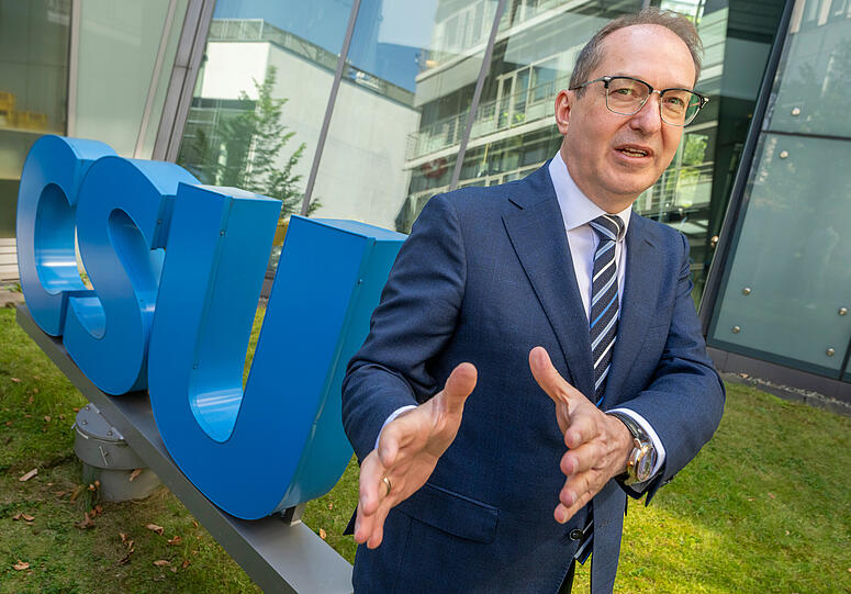 Der designierte Bundesinnenminister Alexander Dobrindt steht im Innenhof der CSU-Parteizentrale neben dem CSU-Logo.