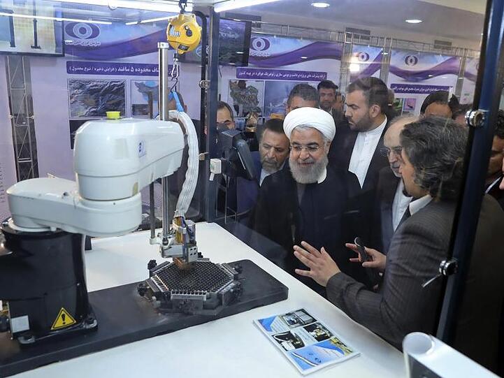 Irans Präsident Hassan Ruhani (M.) lässt sich neue Entwicklungen in der atomenergie im Rahmen des "Nationalen Atomtags" erklären.