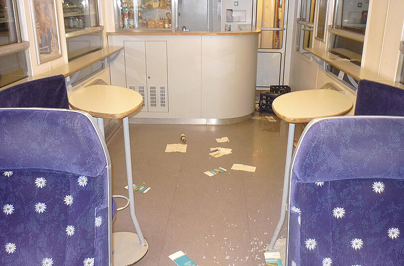 Glasscherben, Flyer und Getränkepfützen sind auf dem Boden.