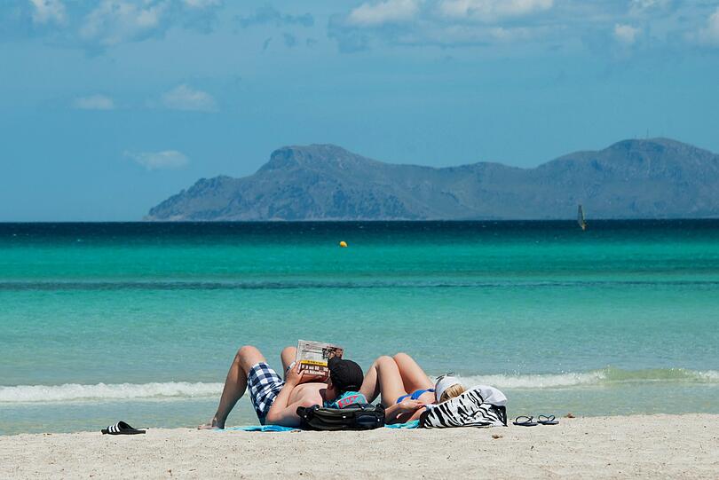 In diesem Jahr ein ferner Traum: Urlauber liegen am Strand an der Platja de Muro im Norden der Mittelmeerinsel Mallorca.