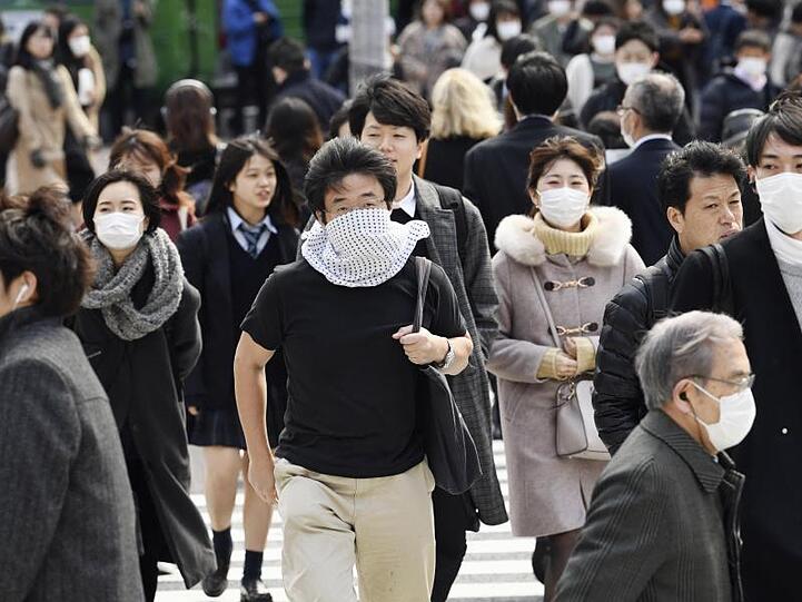 Wegen des Coronavirus tragen viele Passanten in Tokio Mundschutz. Die japanische Regierung erklärt Millionen Visa für Chinesen und Südkoreaner für ungültig.