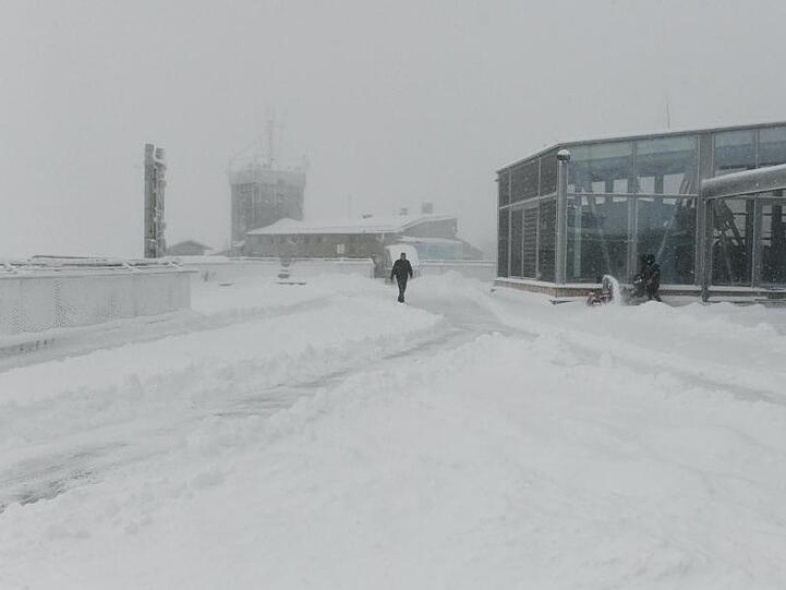 Ein Mann geht über die verschneite Dachterasse von der Zugspitze. Foto: Angelika Warmuth/dpa/Archivbild