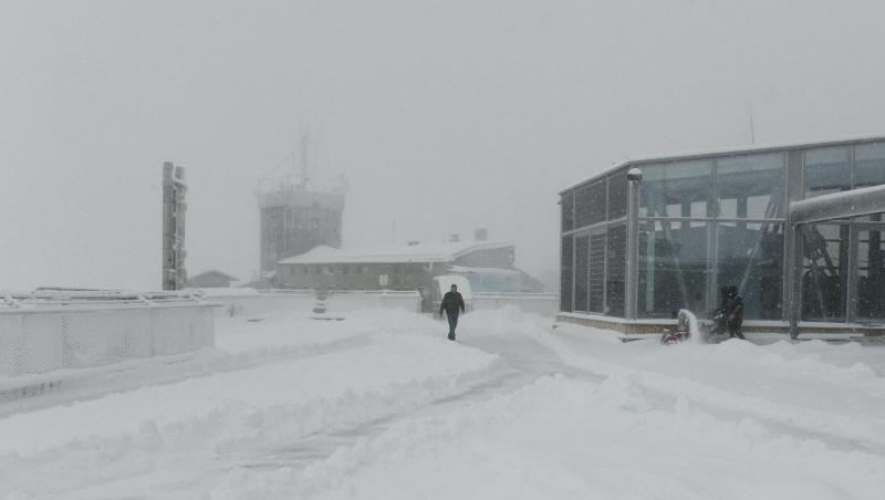 Ein Mann geht über die verschneite Dachterasse von der Zugspitze. Foto: Angelika Warmuth/dpa/Archivbild