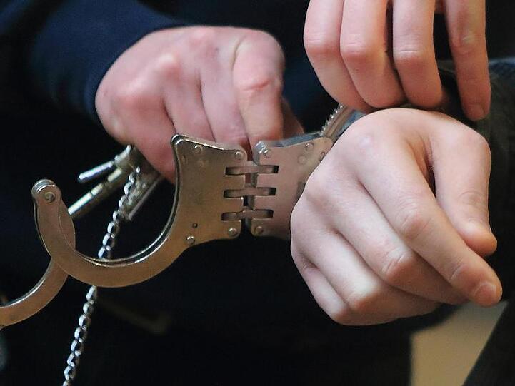 Handschellen werden einem Mann angelegt. Foto: Jens Wolf/Archivbild