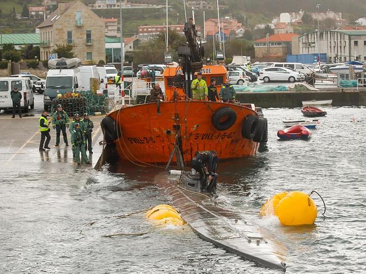 Ein Schlepper der Guardia Civil zieht ein gut 20 Meter langes Drogen-U-Boot aus dem Wasser, das vor der Küste der Region Galicien abgefangen worden war.