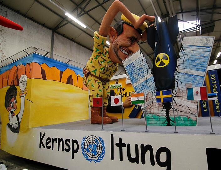 Eine Pappfigur, die den iranischen Präsidenten Mahmud Ahmadinedschad darstellt, wie er mit einer Atombombe die UN-Zentrale spaltet, steht in der Wagenbauhalle des Festkomitees in Köln auf einem Motivwagen für den Rosenmontagszug.