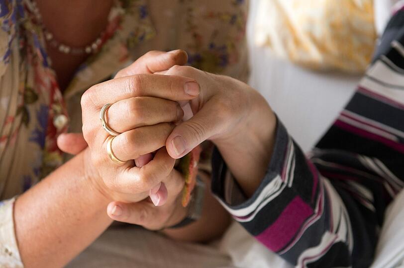Eine Therapeutin (l) hält im Hospiz St. Martin in Stuttgart die Hand einer todkranken Bewohnerin. (Symbolbild)