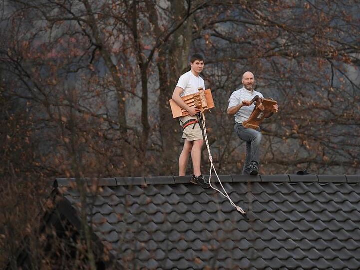 Anton Neff (l) und Stefan Klotz stehen auf dem Dach eines Wohnhauses und drehen die Osterratschen. Foto: Angelika Warmuth/dpa