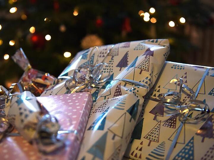 Geschenke liegen vor einem Tannenbaum.
