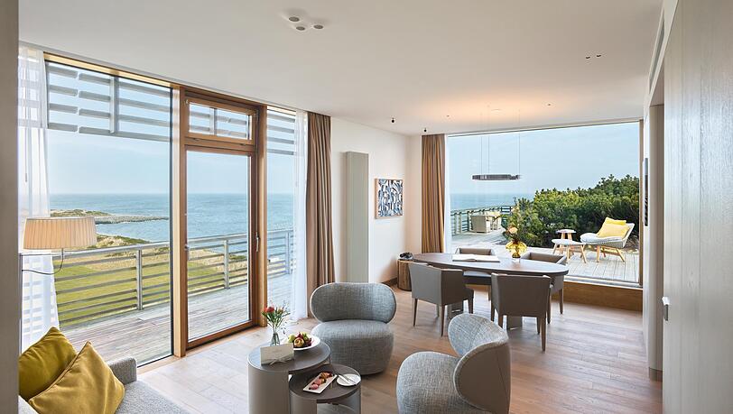 Eine der neuen Suiten mit bodentiefen Fenstern und Rundum-Blick auf D&uuml;nen und Meer.