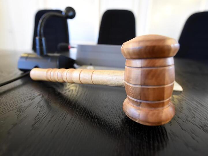Auf einer Richterbank liegt ein Richterhammer aus Holz. Foto: Uli Deck/dpa/Symbolbild