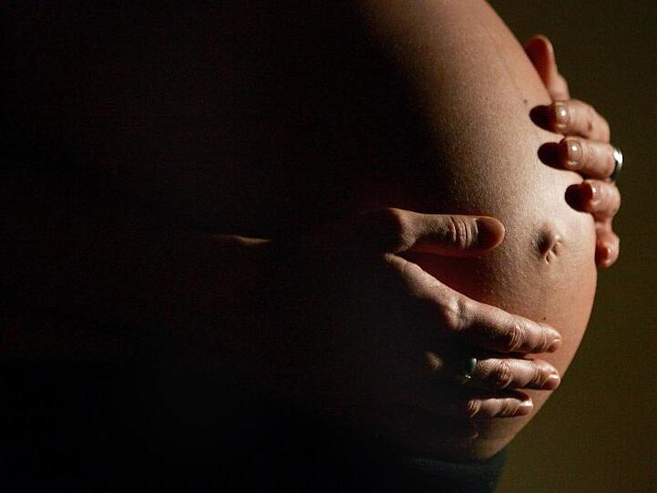 Eine hochschwangere Frau fasst sich mit beiden Händen an ihren Bauch. Auch Nicht-Trinker leiden in vielen Fällen unter den Folgen von Alkoholkonsum.