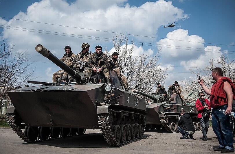 Pro-Russische Kräfte machen Fotos von den übergelaufenen ukrainischen Soldaten, die auf ihren gepanzerten Fahrzeugen sitzen.