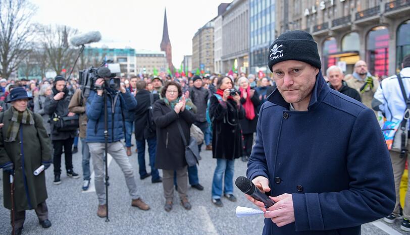 Der Präsident des Fußballclubs FC St. Pauli läuft mit Teilnehmern einer Gegendemonstration zur Kundgebung "Merkel muss weg!" laufen den Jungfernstieg.