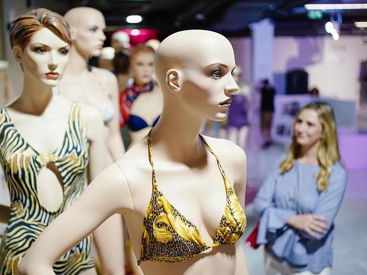 Eine Frau betrachtet bei einem Presserundgang vor der Eröffnung des Bikinimuseums an Puppen angebrachte historische Bikini-Luxusmodelle aus den 1940er bis 1990er-Jahren. Foto: Uwe Anspach/dpa