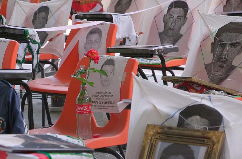 In der Aula des Lehramtsseminar von Ayotzinapa/Guerrero ein Mahnmal mit 43 leeren Stühlen. Fotos und persönliche Erinnerungsstücke sollen an das Verbrechen vom 26. September 2014 und die 43 von der Polizei verschleppten Studenten erinnern. Auch bei diesem Einsatz gegen Studenten waren G36-Sturmgewehre von Heckler & Koch im Einsatz, obwohl der Export der Waffen in den Bundesstaat Guerrero von der Bundesregierung untersagt worden war.
