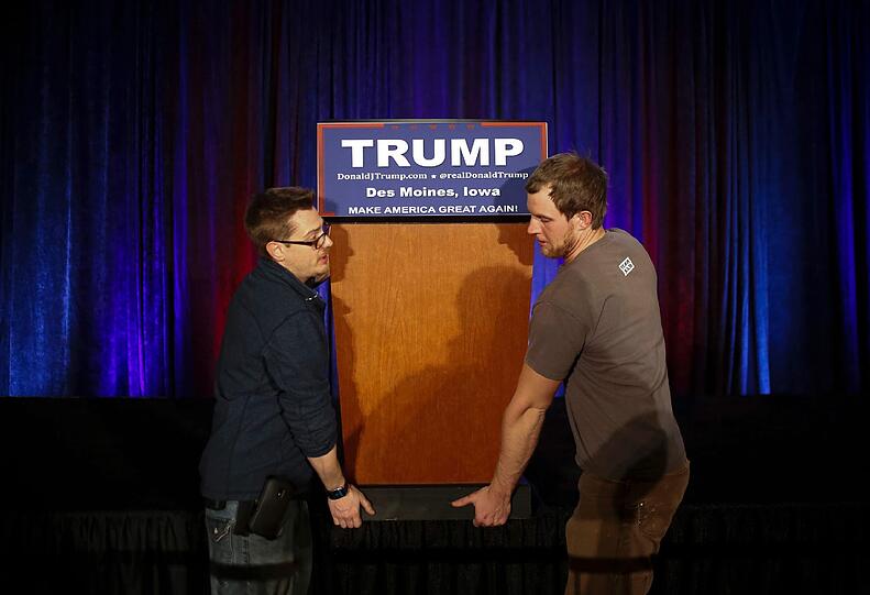 Wird nicht mehr gebraucht: Helfer tragen das Rednerpult von Donald Trump in Iowa weg - in dem US-Bundesstaat fanden die ersten Vorwahlen der Präsidentschaftskandidatur statt...