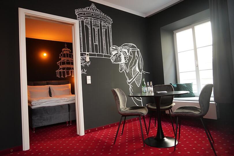 Dackel Waldi trifft Monopteros. In dieser Suite erinnert nur der rote Teppich mit weißen Edelweißblümchen an das frühere Hotel.