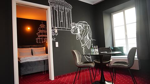 Dackel Waldi trifft Monopteros. In dieser Suite erinnert nur der rote Teppich mit weißen Edelweißblümchen an das frühere Hotel.