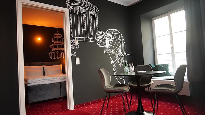 Dackel Waldi trifft Monopteros. In dieser Suite erinnert nur der rote Teppich mit weißen Edelweißblümchen an das frühere Hotel.