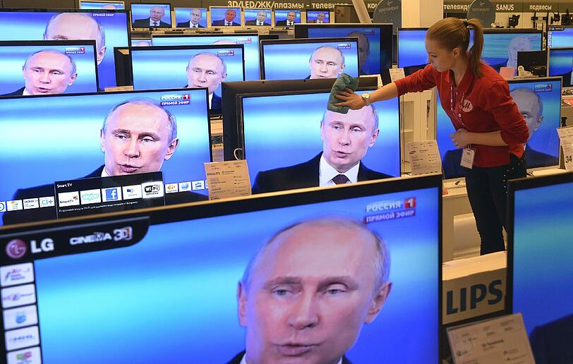 Eine Antgestellte putzt einen TV-Bildschirm in Moskau während Präsident Putins Frage und Antwort-Session im russischen TV. Putin beschuldigte heute Ukraine's neue Autoritäten das Land an einen Abgrund zu führen aber bekräftigte nochmal, der Dialog sei der einzige Weg das Land aus der Krise zu führen.
