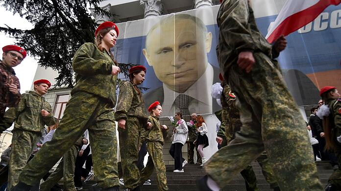Uniformierte Jugendliche marschieren in Jalta anlässlich einer Aktion zum neunten Jahrestag der Krim-Annexion an einem Bild des russischen Präsidenten Wladimir Putin vorbei.