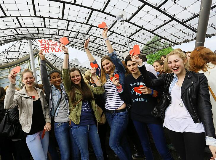 "One Direction" spielen am Freitag in der Olympiahalle. Jubelnde Fans warten im Regen vor der Olympiahalle.