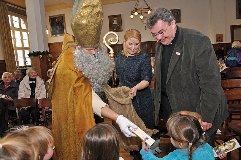 Der Nikolaus, Maite Kelly und Monsignore Georg Austen verteilen Schokonikoläuse an die Kinder des Kinderhauses St. Anton.