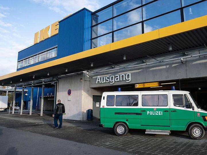 Ein Fahrzeug der Spurensicherung der Polizei steht vor einem Seiteneingang eines Ikea-Möbelhauses im Stadtteil Nieder-Eschbach, nachdem hier ein Geldbote angeschossen und schwer verletzt worden war.