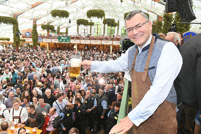 Staatsminister Florian Herrmann hält nach dem Anstich im Hofbräuzelt ein Bier in der Hand.