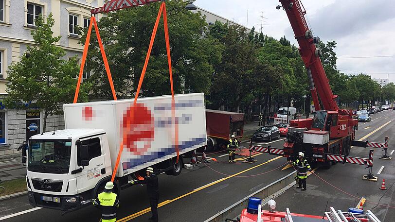 Mit einem Kran musste die Münchner Feuerwehr den schrägen Lkw wieder auf die Fahrbahn heben.