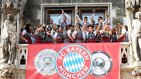 Spielerinnen und Spieler von Bayern München jubeln auf dem Rathaus-Balkon.