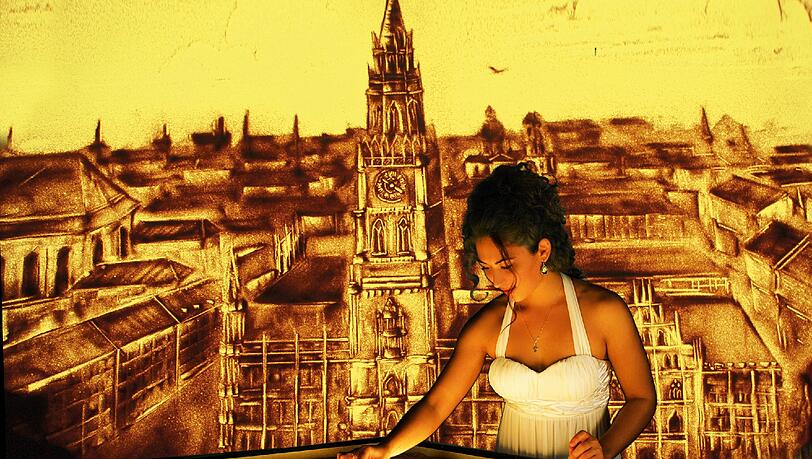 Die Künstlerin malt, eine Kamera filmt: So entstehen auf der Leinwand immer neue Sandbilder von München. Die Künstlerin malt, eine Kamera filmt: So entstehen auf der Leinwand immer neue Sandbilder von München.