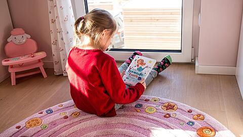 So sieht es im Frühjahr 2020 in vielen Kinderzimmern aus: Ein kleines Mädchen blättert allein in einem Buch.