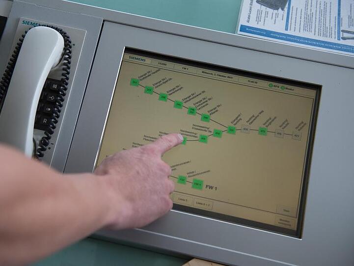 Ein Feuerwehrmann drückt den Touchscreen der Feuerwehrdurchgangsschaltung, um den Fahrzeugen im Einsatz die Ampeln auf grün zu schalten. Foto: Timm Schamberger/dpa