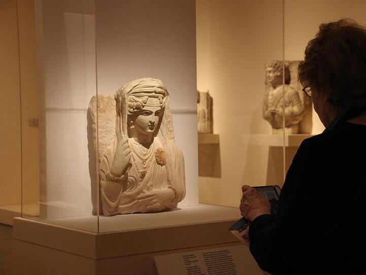Besucher stehen vor einer antiken Stein-Büste der Bat'a, Tochter von Moqim, (Enkelin von) Malku aus Palmyra, die nach Expertenschätzungen im späten 2. oder frühen 3. Jahrhundert nach Christus entstanden sein soll.