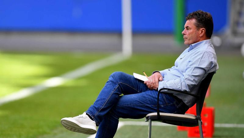 Dieter Hecking, Trainer des Hamburger SV, sitzt auf einem Stuhl am Spielfeldrand.
