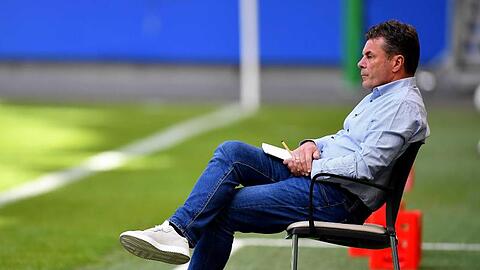 Dieter Hecking, Trainer des Hamburger SV, sitzt auf einem Stuhl am Spielfeldrand.