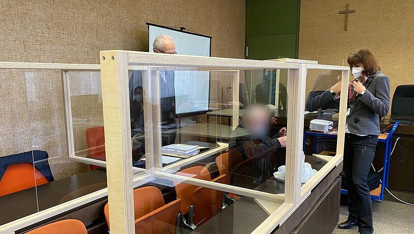Der angeklagte Vater (m.) sitzt zusammen mit seinem Anwalt und einer Übersetzerin vor dem Prozess im Landgericht München I.