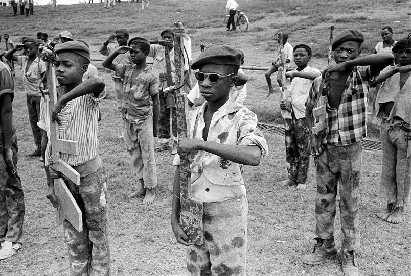 Jungen des Katangese Youth Movements tragen improvisierte Uniformen, die sie selbst gestaltet haben. Sie trainieren mit hölzernen Gewehren im kongolesischen Elisabthville.
