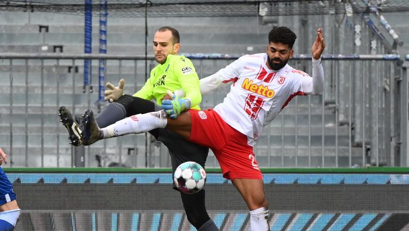 Der Karlsruher Torhüter Marius Gersbeck (l) und der Regensburger Andre Becker kämpfen um den Ball.