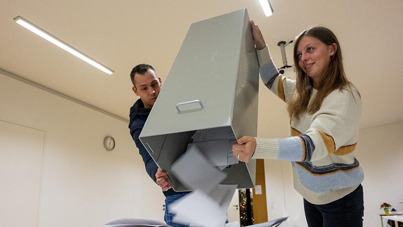 Sarah Heinzelmann und Sven Harder leeren eine Wahlurne mit Wahlzetteln.
