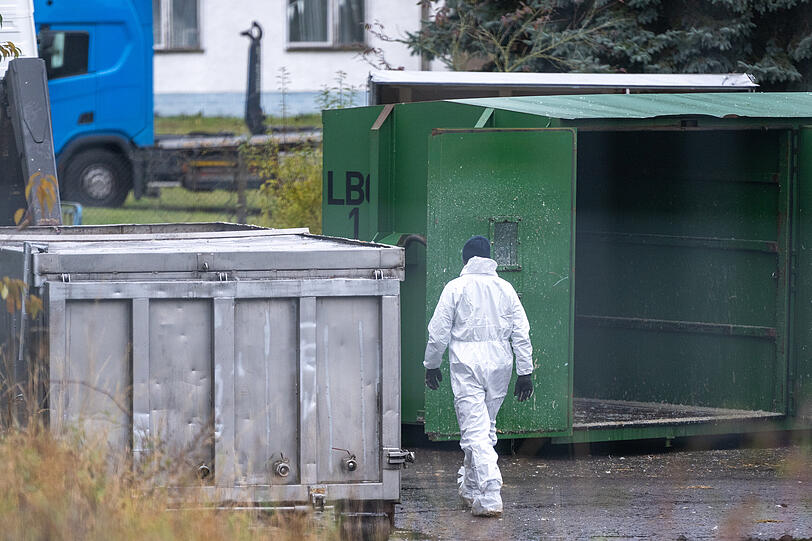Ein Mann mit weißem Schutzanzug geht über eine von Geflügelpest befallene Anlage.