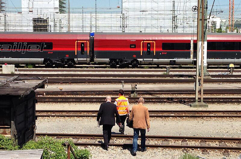 Ein Bahnarbeiter führt zwei kriminalpolizisten zum Railjet, in dem das Neugeborene getötet wurde.