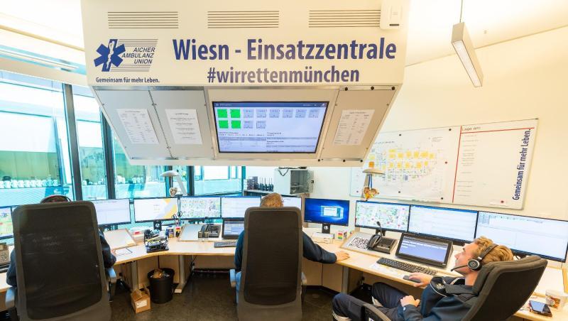 Drei Männer sitzen in der Wiesn-Einsatzzentrale der Sanitätsstation auf dem Oktoberfestgelände und richten die Anlage ein. Foto: Peter Kneffel