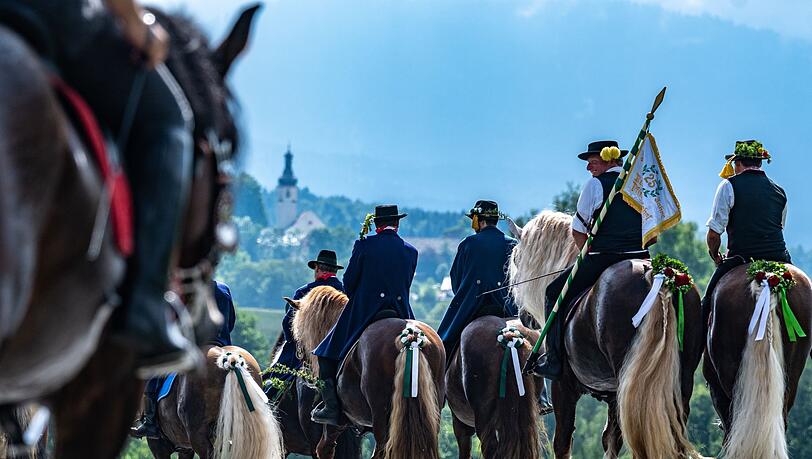 Teilnehmer des Kötztinger Pfingstritts reiten mit ihren Pferden auf einer Straße.